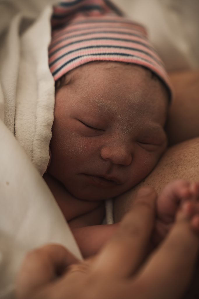 Newborn baby Lily sleeping in a striped hospital hat, birth at the AMC Amsterdam with doula support