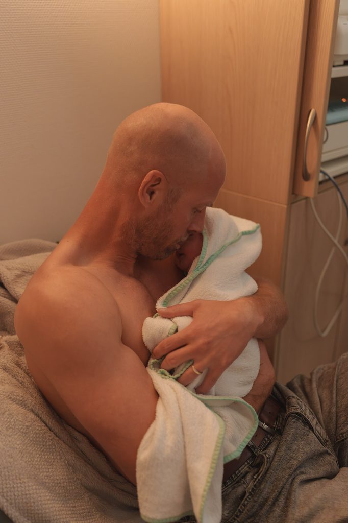 Father holding his newborn daughter skin to skin, doula support at a hospital birth in Arnhem