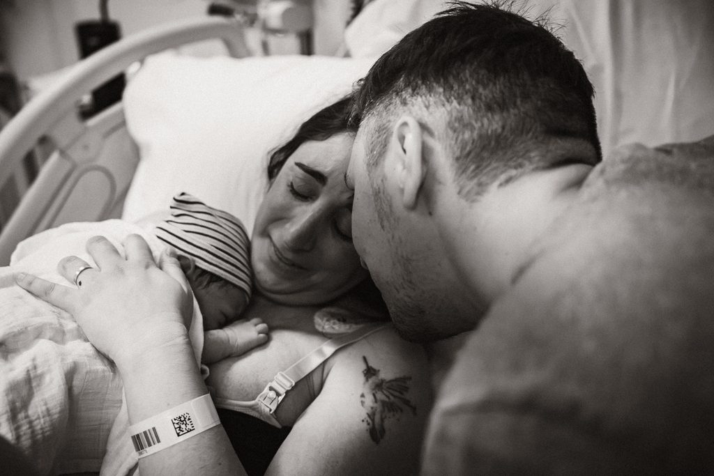 Parents cuddling their newborn daughter after the birth, black and white, birth at the AMC Amsterdam with doula support